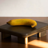 Banane artificielle jaune Sia Deco sur plateau en bois marron foncé