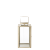 Lanterne en métal mat effet brossé doré avec anse carrée, dessus carré et plat. Avec fenêtres transparentes en verre. Structure dorée en acier inoxydable.