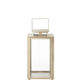 Lanterne en métal mat effet brossé doré avec anse carrée, dessus carré et plat. Avec fenêtres transparentes en verre. Structure dorée en acier inoxydable.