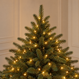 Vue rapprochée du feuillage vert très dense du sapin Fluffy 180 cm éclairé par ses LED blanc chaud