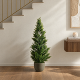 Cyprès artificiel 120 cm en pot posé au sol dans une entrée contemporaine beige, près d'un escalier et d'une console en bois