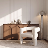 Fauteuil MILA en tissu bouclette crème dans un salon parisien à moulures, devant un buffet en bois et un lampadaire chromé, Sia Deco