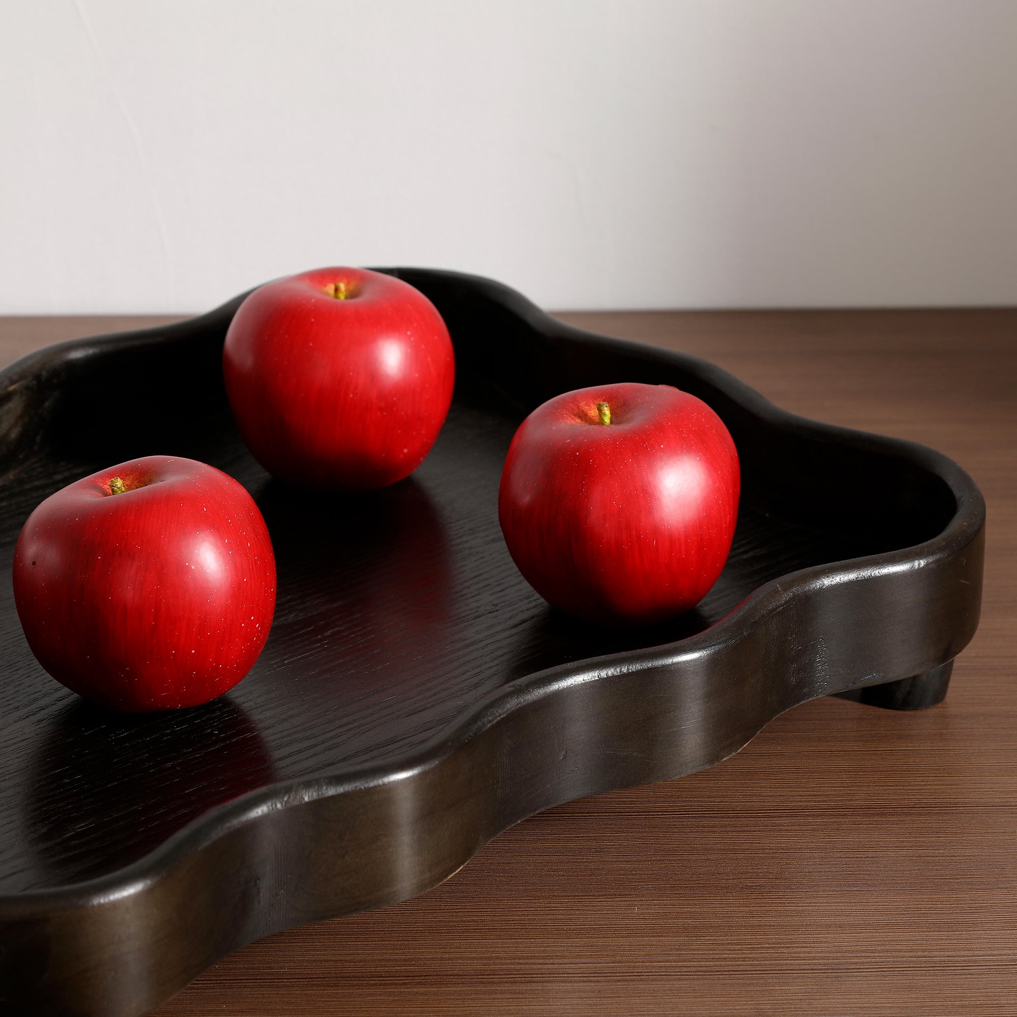 Pommes artificielles rouges foncé Sia Deco sur un plateau en bois noir ondulé
